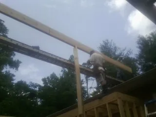 Carpenter setting a ridge beam over a new addition frame — Ice Dam Removal by Roofing Brothers in Foss