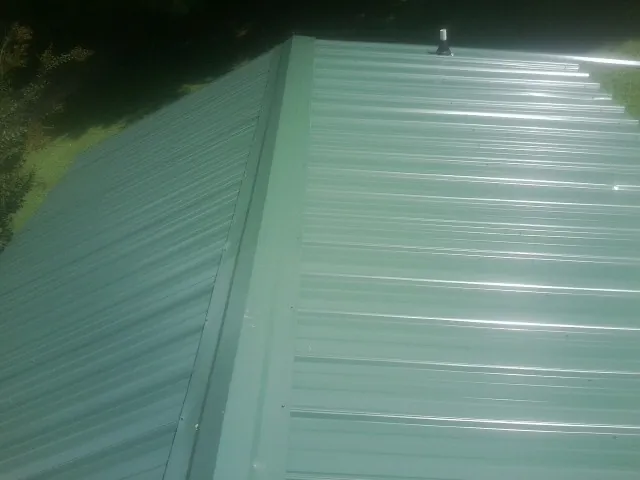 New green metal panels meeting at the ridge of a roof — Flat Roof Repair work by our crew in Foss