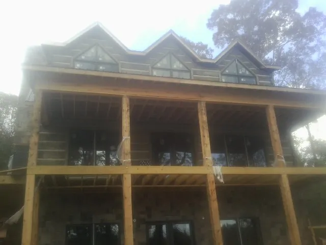 Dormers and porch framing on a large log home under construction — Roof Coating work by our crew in Foss