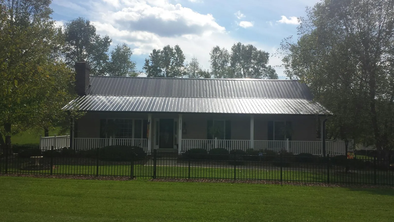 Gray metal roof on a brick ranch with a full width front porch — Gutter Guard Installation work by our crew in Foss