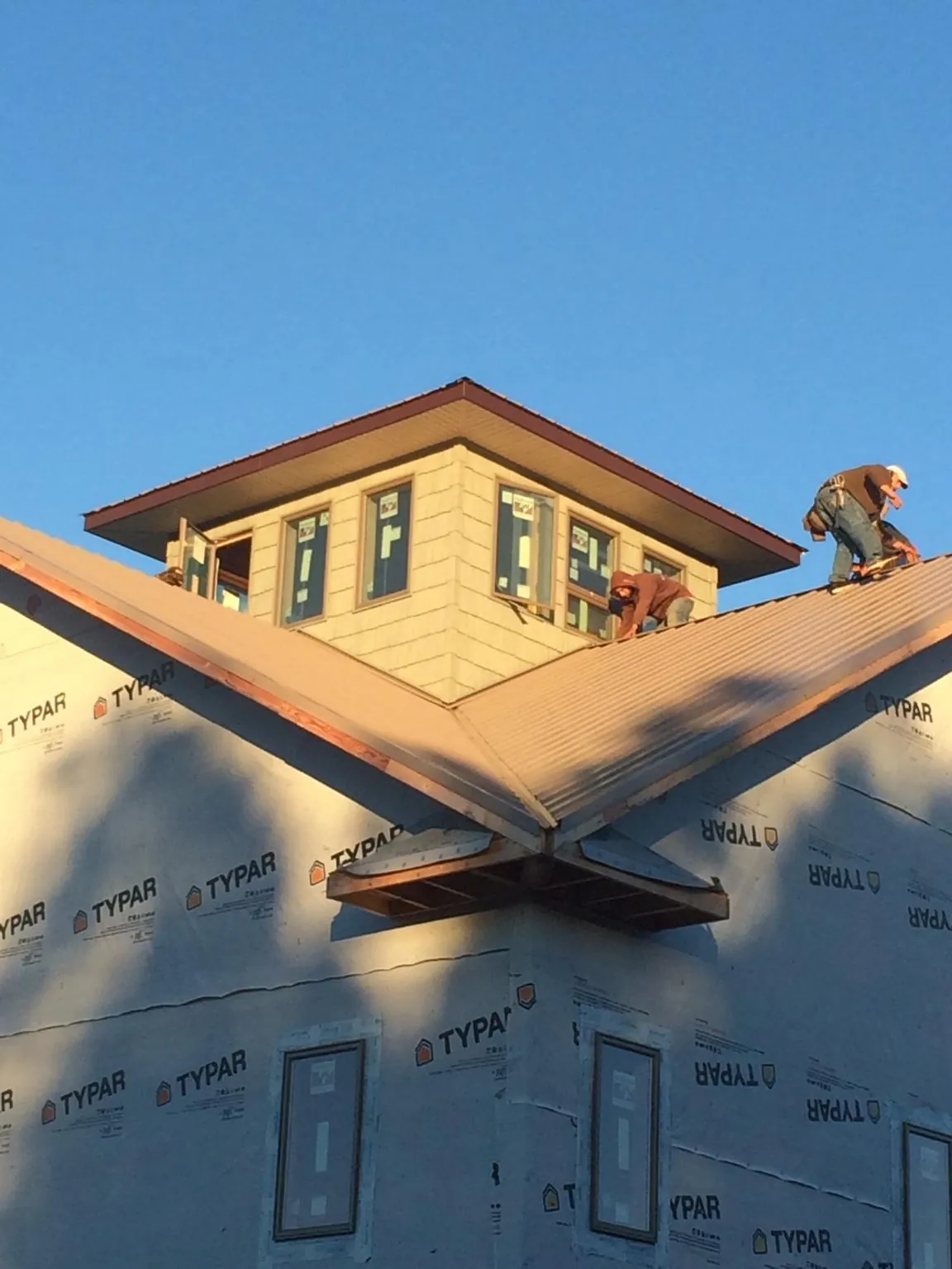 Roofers working around a rooftop cupola on a new metal roof at sunset — Roof Waterproofing in Foss by Roofing Brothers